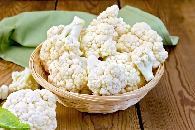 Cauliflower in a wicker basket on a wooden boards background