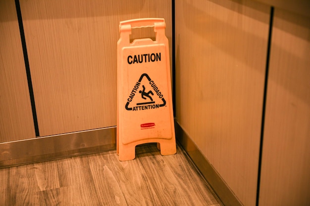 A caution sign is on a caution stand in a kitchen.