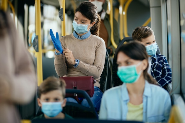 Осторожная женщина в маске для лица в защитных перчатках во время поездки на автобусе