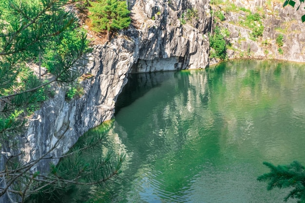 사진 절벽 기슭에 있는 동굴. 산에 있는 큰 동굴의 푸른 물. 아름다움을 향한 여행