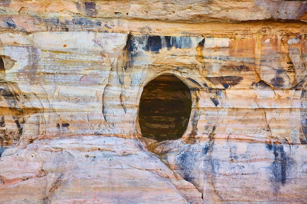 Cave opening in Pictured Rocks cliff wall of gold rust and mineral colors