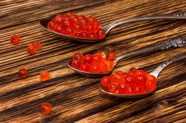 Caviar in spoons on a wooden background