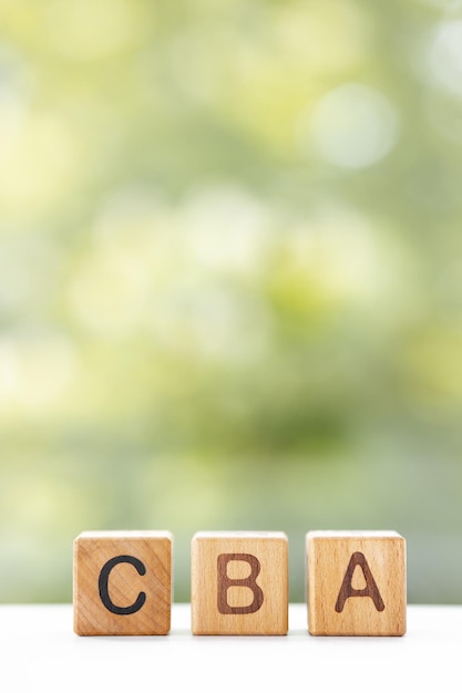 CBA word is written on wooden cubes on a green summer background Closeup of wooden elements