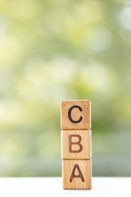 CBA word is written on wooden cubes on a green summer background Closeup of wooden elements