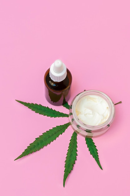 Cbd-cannabishennepcrème en serum of olie met marihuanablad op roze verticale achtergrondafbeelding