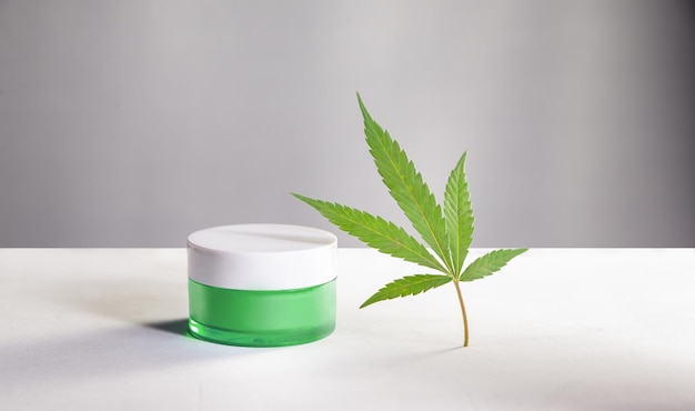 CBD cream, hemp extract, cannabis leaf on white background, skin treatment, natural cosmetology