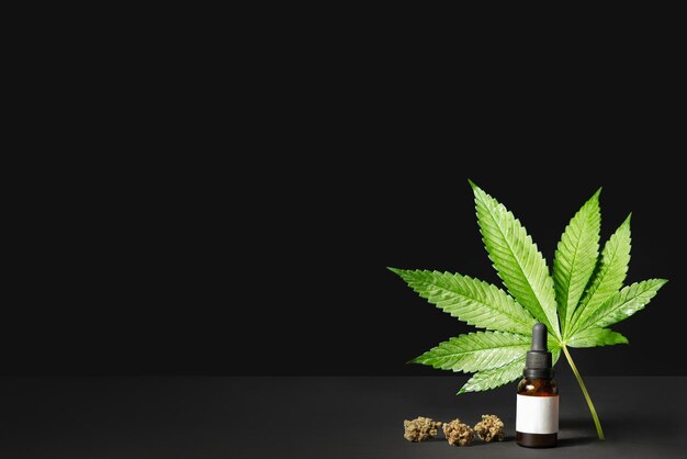 CBD dropper, hemp oil extract, cannabis leaf on black background