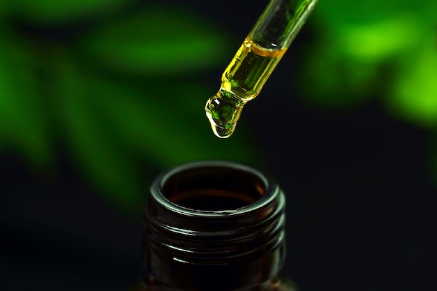 CBD hennepolie Hand met druppel cannabisolie tegen zwarte achtergrond