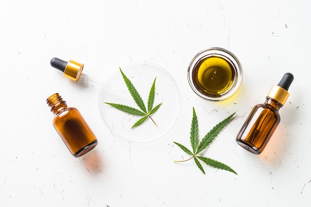 Photo cbd oil and cannabis leaves at white table