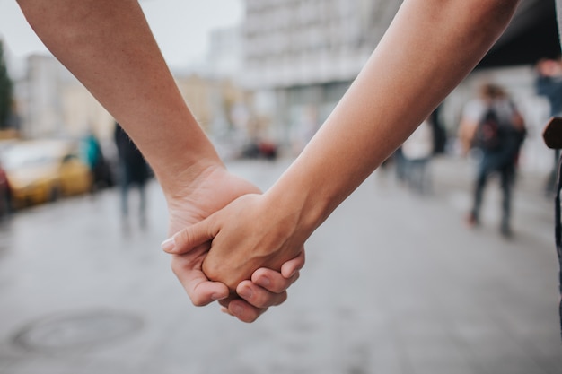 Ccoppia mani chiuse insieme all'aperto in amore e relazione romantica. primo piano del corpo. uomo e donna in città.