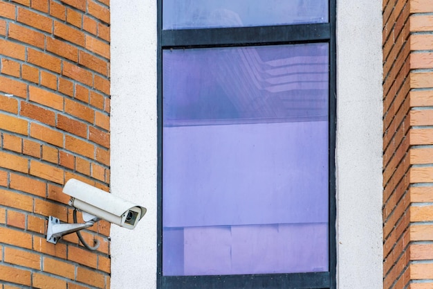 CCTV cameras are installed on the brick wall at the entrance to the supermarket Security and antitheft systems A surveillance camera and an armored window in the bank