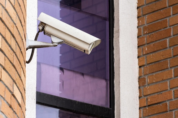 CCTV cameras are installed on the brick wall at the entrance to the supermarket Security and antitheft systems A surveillance camera and an armored window in the bank