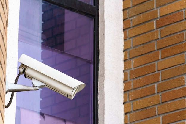 CCTV 카메라는 슈퍼마켓 입구의 벽돌 벽에 설치되어 있습니다. 보안 및 도난 방지 시스템 은행의 감시 카메라 및 장갑 창
