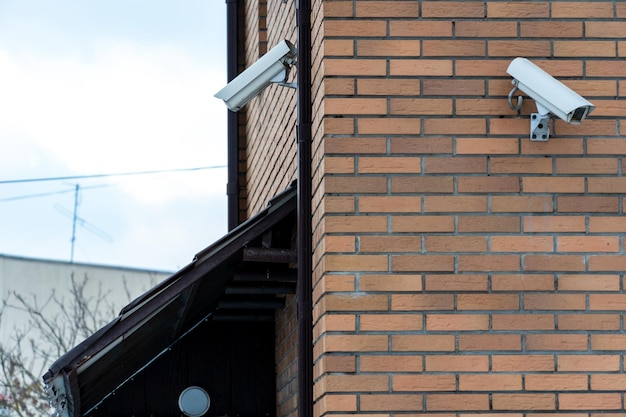 CCTV cameras are installed on the brick wall at the entrance to the supermarket Security and antitheft systems A surveillance camera and an armored window in the bank