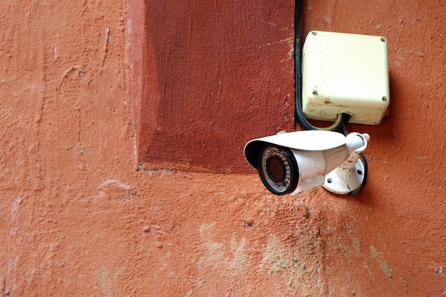 Photo cctv security camera at the building in the city with orange wall background