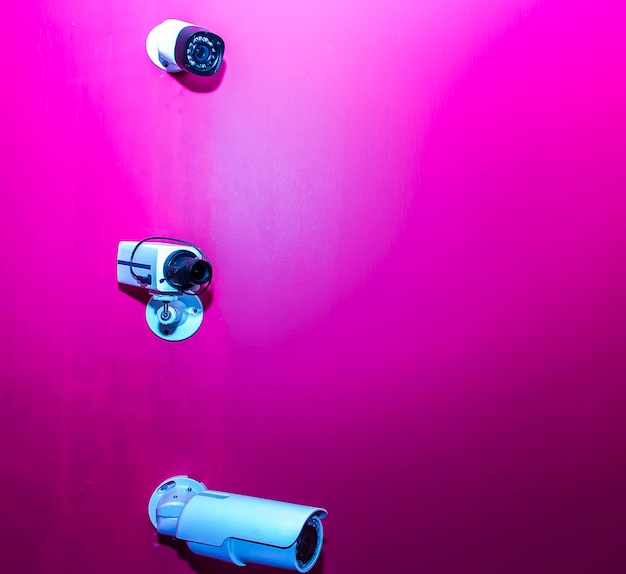 Камера видеонаблюдения над розовой стеной