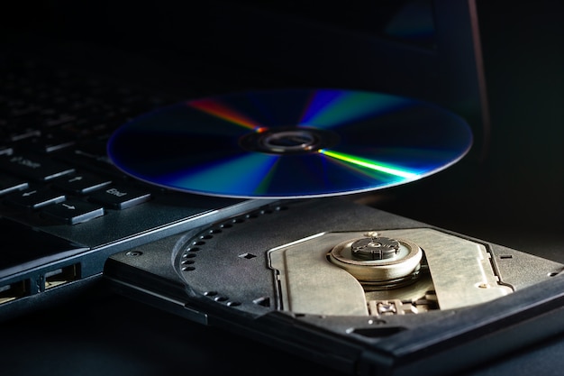 Cd sul computer notebook cd rom nell'oscurità. concetto di progressi tecnologici nei sistemi di registrazione dei dati informatici.