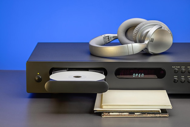 CD player and headphones for listening to music closeup Blue background CD in envelopes