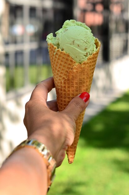 Ce cream in a cone close-up in the girl's hand.