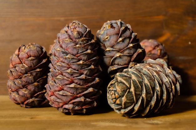 Cedar cones on brown wooden background Cones of Siberian cedar stacked in pile on an wooden board