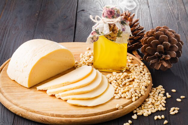 Olio di cedro in bottiglia, noci di cedro, cucchiaio su legno con formaggio