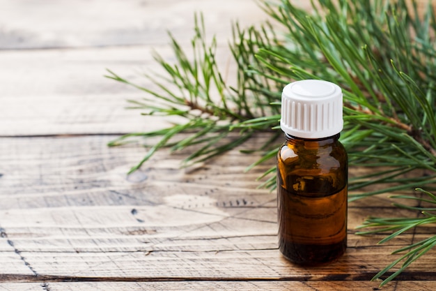 Cedar and spruce essential oil in small glass bottles on wooden table. 