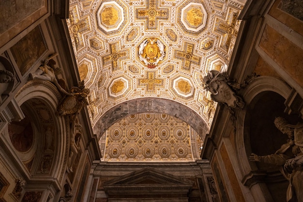 The ceiling of a building is decorated with gold and white designs