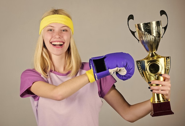 Photo celebrate victory boxing champion athletic girl boxing glove and golden goblet woman wear sport outfit girl cheerful boxer winner boxing is my hobby success in boxing sport achievement