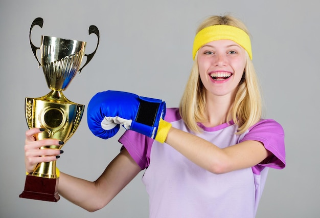 Celebrate victory. Boxing champion. Athletic girl boxing glove and golden goblet. Woman wear sport outfit. Girl cheerful boxer winner. Boxing is my hobby. Success in boxing. Sport achievement.