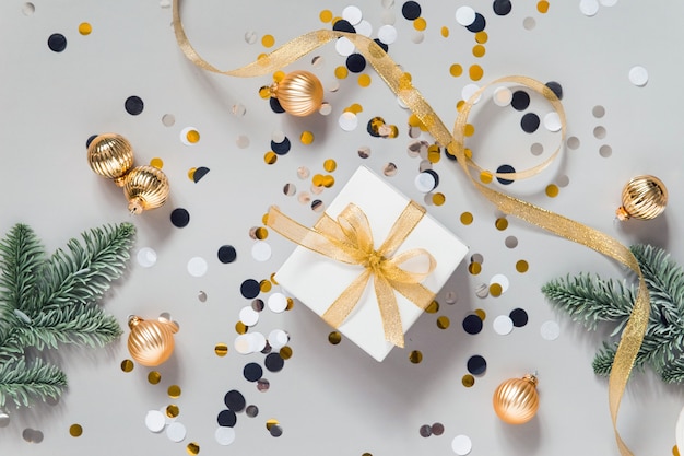 Celebrando la disposizione piatta con decorazioni di capodanno, palline dorate, coriandoli e rami dell'albero di natale