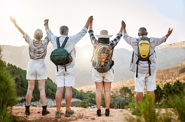 Photo celebrating freedom fun and hiking with a group of senior friends taking a mountain hike and enjoying the view rearview of retired friends spending time together and bonding in the forest or woods