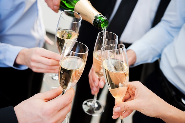 Celebrating great success. Close-up of business people holding flutes with champagne and toasting