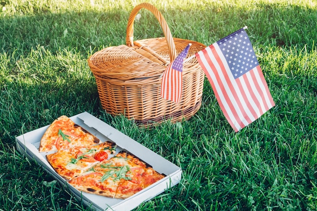 Celebrating Independence Day of America with pizza. Picknick basket with USA flag.