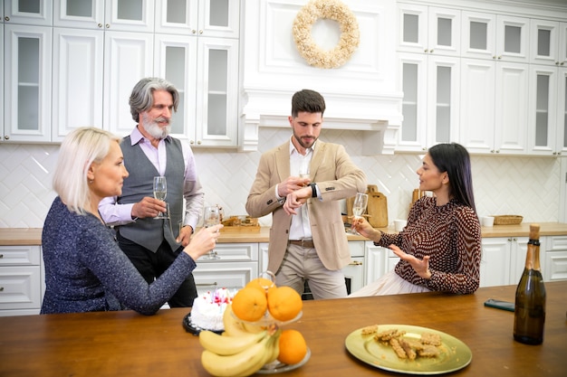 celebrating  in kitchen at home while man looking at watch reminding that he and wife need to leave