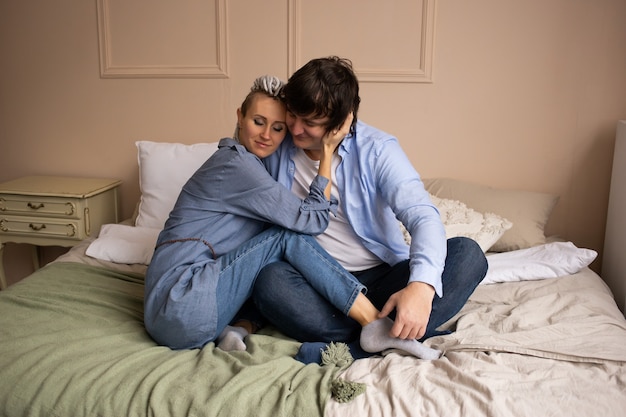 Celebrando il giorno di san valentino. coppia in camera da letto seduto sul letto e abbracciare.