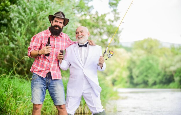 Celebrating success hobby and sport activity mature man fisher celebrate retirement summer family weekend father and son fishing two fishermen with fishing rods retired businessman friendship