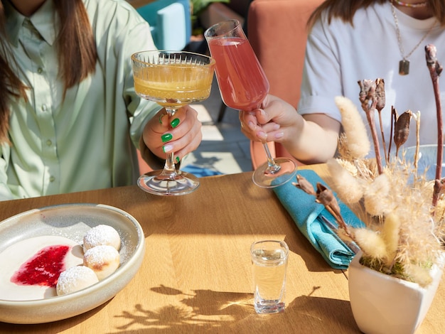 楽しい時間を過ごしている幸せな女性の友人の手でアルコールのグラスで祝う