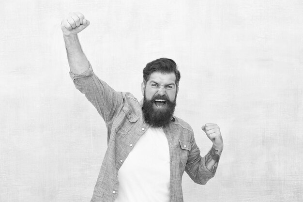 Celebration concept Brutal handsome hipster man on grey wall background Bearded man trendy hipster style Cheerful mood Happiness and joy Hipster with beard and mustache happy expression