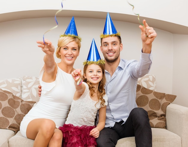 Celebration, family, holidays and birthday concept - happy\
family in blue hats with cake