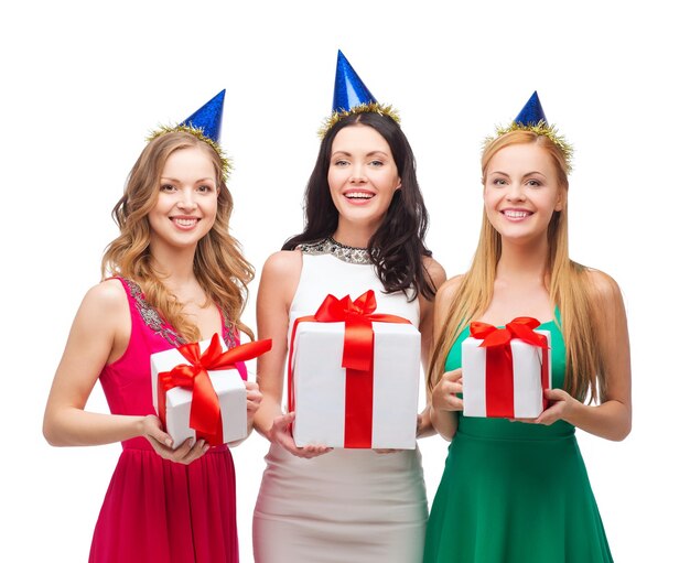 celebration, friends, bachelorette party, birthday concept - three smiling women wearing blue hats with gift boxes