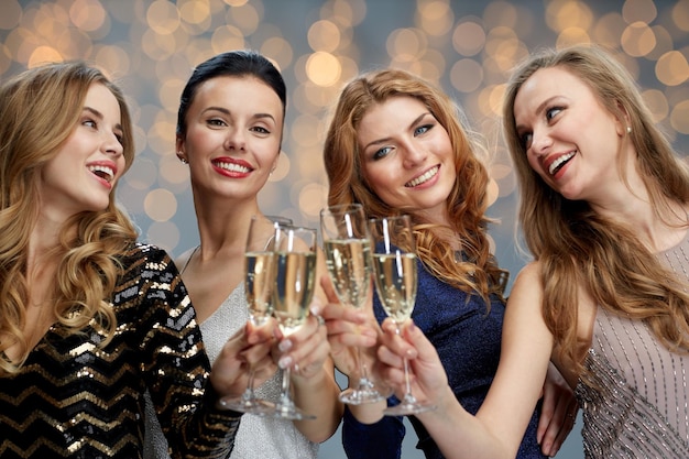 celebration, friends, bachelorette party and holidays concept - happy women clinking champagne glasses over lights background