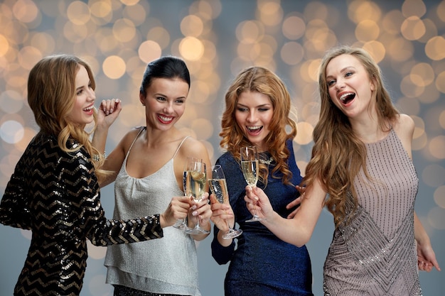 celebration, friends, bachelorette party and holidays concept - happy women clinking champagne glasses over lights background