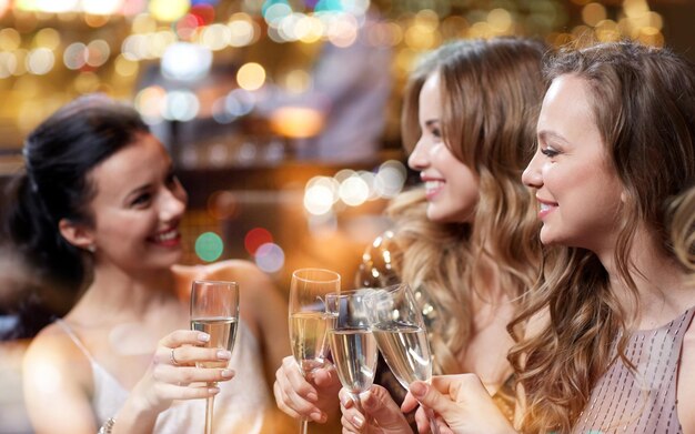 celebration, friends, bachelorette party and holidays concept - happy women with champagne glasses at night club