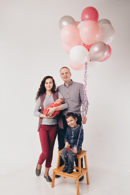 Celebrazione, divertimento, famiglia alla festa. adulti e bambini su uno sfondo bianco tra le palline colorate festeggiano il loro compleanno