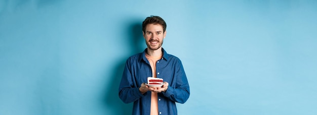 Foto celebrazione e concetto di vacanza uomo sorridente che tiene la torta di compleanno con la candela e che sembra felice stan