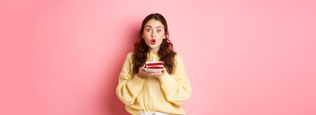 Celebration and holidays excited birthday girl holding bday cake with candle and looking surprised a