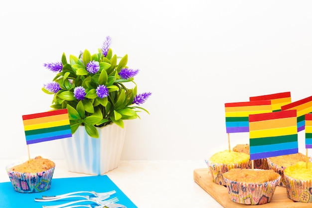 Celebration of pride day with flags on cupcakes, with a flower in a pot on white background