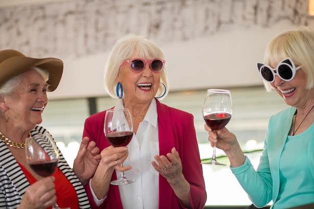 Celebrazione. tre signore felici anziane che si divertono e bevono vino