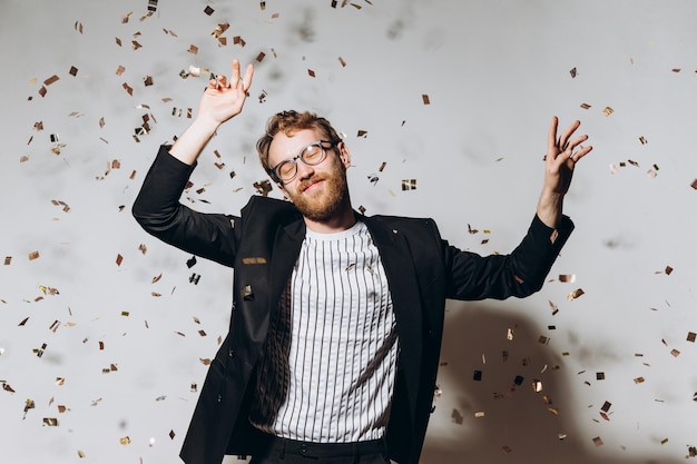 Celebration time Portrait of a happy guy dancing under glittering confetti