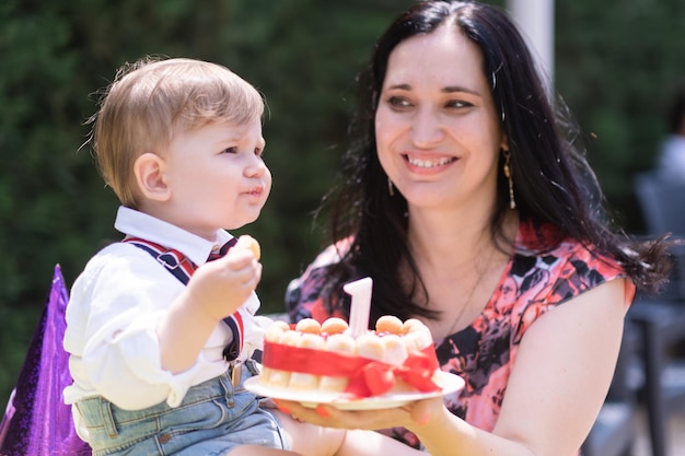 Празднование годовалого мальчика и его матери, особый день, наслаждаясь свечой на праздничном торте